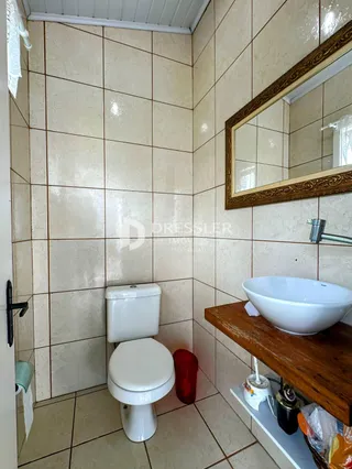 Foto de um banheiro com revestimento de azulejos claros e vaso sanitário branco.