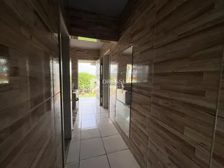 Corredor interno com revestimento de madeira e piso cerâmico.