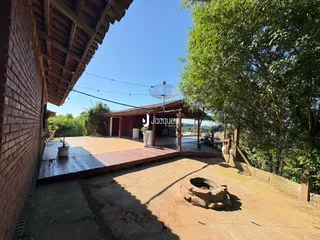 Vista externa de uma área de lazer com deck de madeira e parede de tijolos.