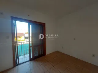 Interior de uma sala com porta de vidro abrindo para uma área externa.