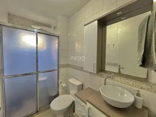 Banheiro com revestimento cerâmico branco e bancada moderna.