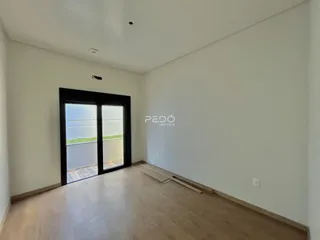Ambiente interno de uma sala com piso de madeira clara e porta de vidro que dá para o exterior.