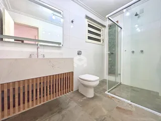 Foto de um banheiro com box de vidro e piso de concreto.