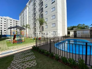 Vista externa de uma piscina e jardim em um condomínio residencial.