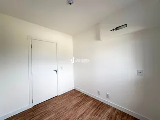 Interior de um ambiente com paredes brancas e piso de madeira clara.