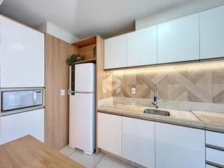 Cozinha moderna com armários brancos e bancadas claras.