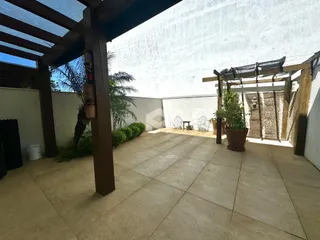 Área externa de pátio com estrutura de madeira e plantas.