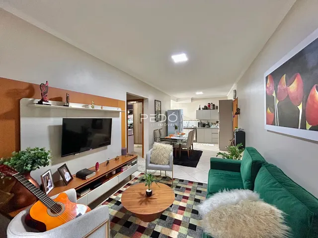 Sala de estar com sofá verde e piso de madeira na residência.