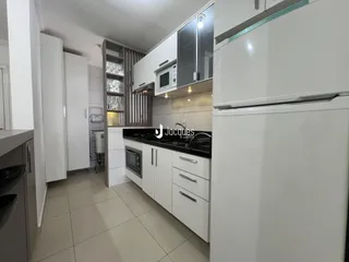A cozinha moderna com armários brancos e piso claro.