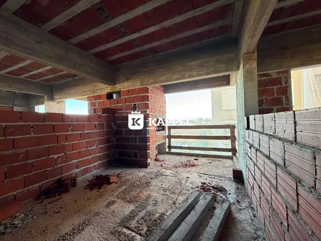 Interior de uma estrutura em construção com paredes de tijolos aparentes e vigas de madeira expostas.