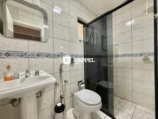 Este é um banheiro com revestimento de azulejos brancos e bancada branca.