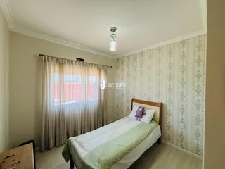 Quarto com cama e cortinas em ambiente claro.