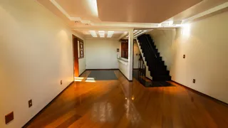 Hall de entrada com piso de madeira e escadaria no interior da residência.