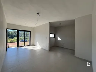 Vista interna de uma sala ampla com piso claro e portas de vidro.