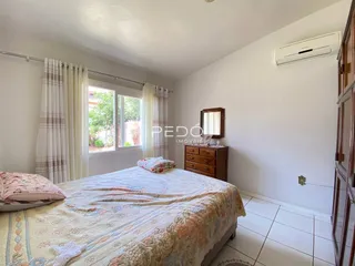 Quarto com cama e janela em ambiente claro.