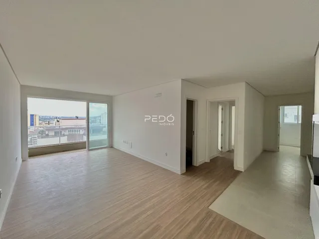 Sala de estar ampla com piso de madeira clara e portas de vidro.