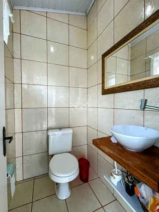 Foto interna de um banheiro com revestimento de cerâmica e pia de apoio.