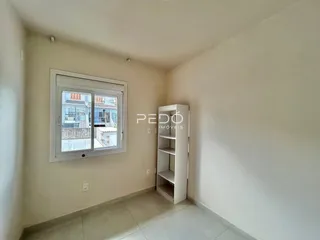 Vista interna de um cômodo com janela e estante branca.
