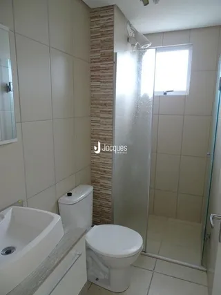 Foto de um banheiro interno com azulejos brancos e louças sanitárias.
