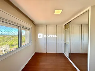 Sala ampla com piso de madeira e grande janela com vista externa.
