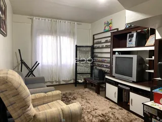 Sala de estar com sofá e janela iluminada em um imóvel no Brasil.