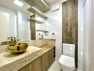 Banheiro moderno com bancada de mármore e louças douradas.