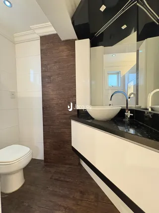 Foto de um banheiro moderno com bancada escura e revestimento de madeira na parede.