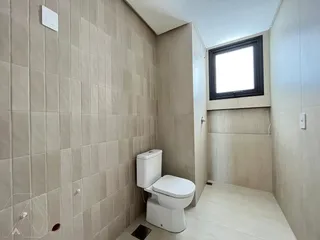 Foto de um banheiro com revestimento de azulejos claros e um vaso sanitário branco.