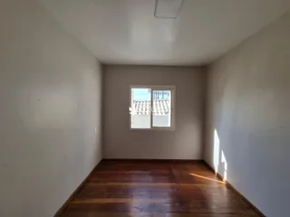 Corredor interno de uma residência com piso de madeira e paredes brancas.