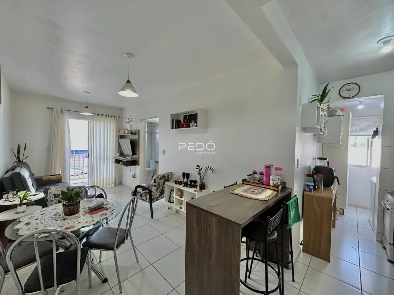 Sala de jantar e estar com piso de cerâmica clara e móveis de madeira.