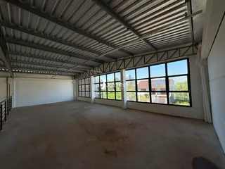 Interior de um espaço amplo com estrutura metálica e grandes janelas.