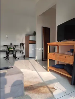 Sala de estar com mesa de jantar e móveis de madeira clara em um apartamento.