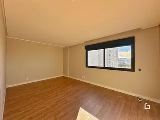 A sala de estar apresenta piso de madeira e uma grande janela com vista.