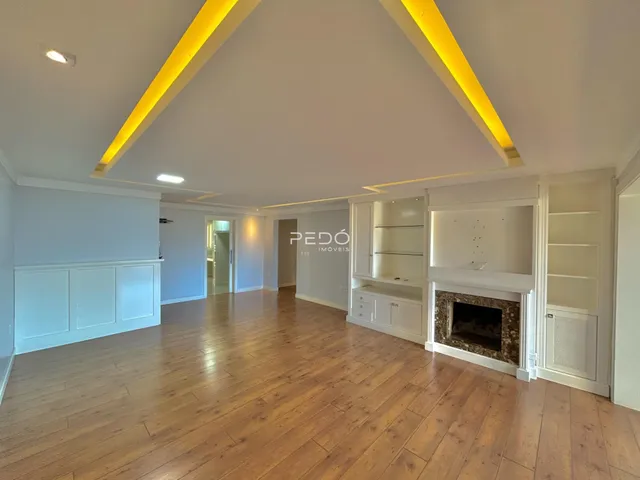 Sala de estar com piso de madeira e teto inclinado em um imóvel em Lajeado.