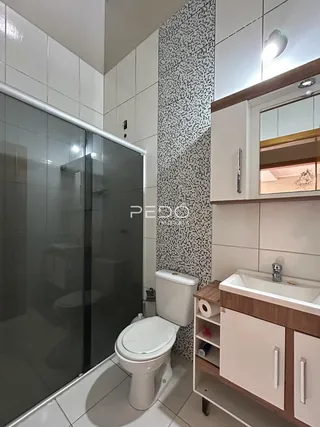 Foto de um banheiro com box de vidro e louças brancas.
