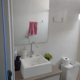 Foto de um banheiro com pia branca e revestimento de azulejos brancos.