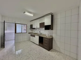 Foto de uma cozinha com armários e piso de cerâmica clara.