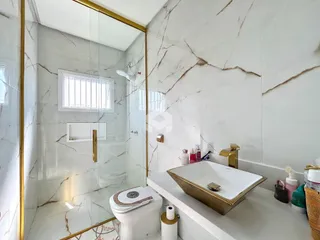 Banheiro com revestimento de mármore e detalhes em dourado.