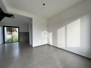 Uma sala de estar com piso de cerâmica e porta de vidro que dá acesso ao exterior.