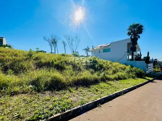 Fachada de uma casa branca com terreno gramado e vegetação ao fundo.