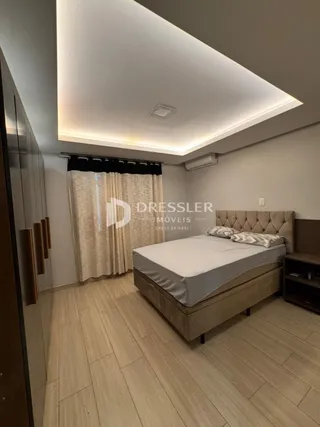 Quarto com cama e piso de madeira em um imóvel.