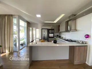 Sala de estar e cozinha moderna com piso de madeira clara.