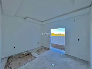 Ambiente interno de uma sala com piso de concreto cru e parede branca.