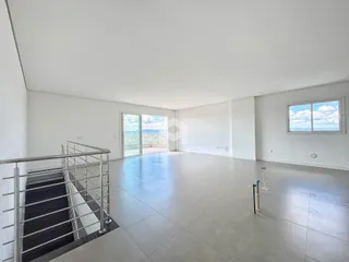 Ambiente interno de uma sala ampla com piso de cerâmica e vista para o exterior.