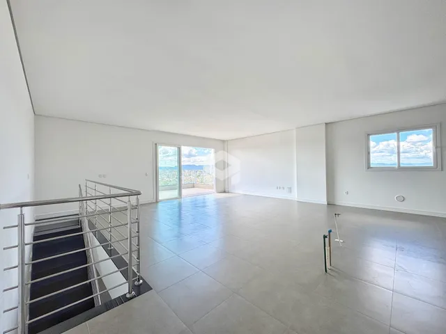 Ambiente interno de uma sala ampla com piso de cerâmica e vista para o exterior.
