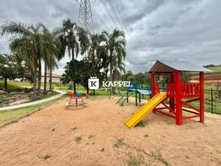 Uma área externa com um playground e árvores de palmeira sob um céu nublado.