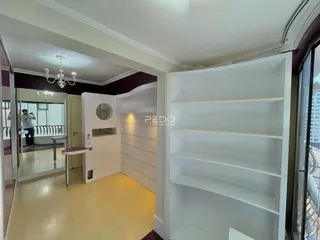 Hall de entrada com parede decorada e estante branca em um imóvel.