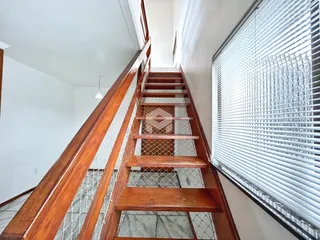 Vista de um corredor com escadaria de madeira no imóvel.