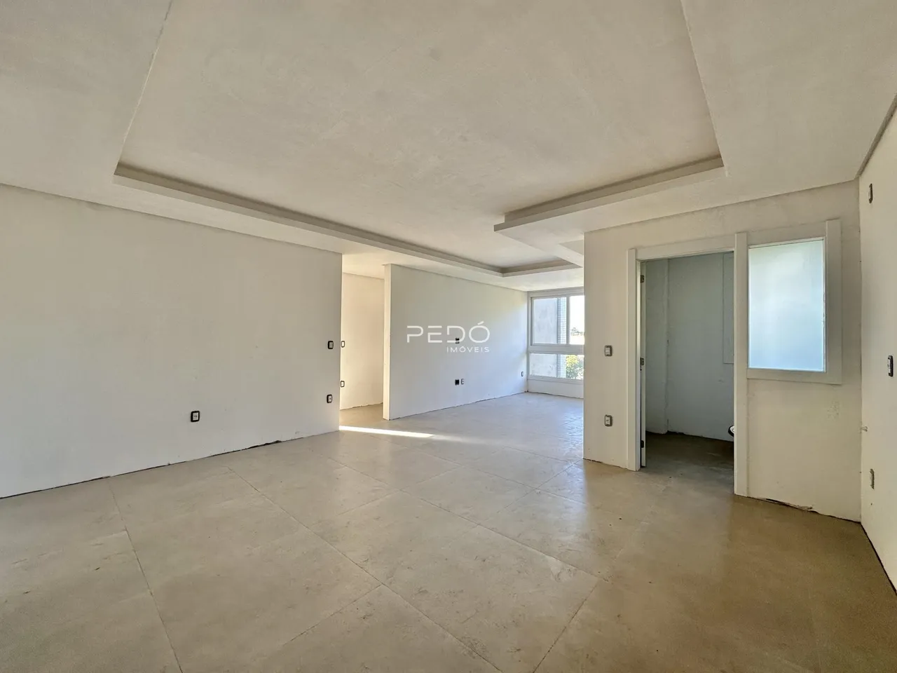 Ambiente interno amplo com paredes brancas e piso de concreto.