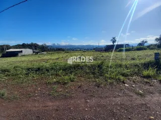 Paisagem de campo com vegetação seca e colinas ao fundo.